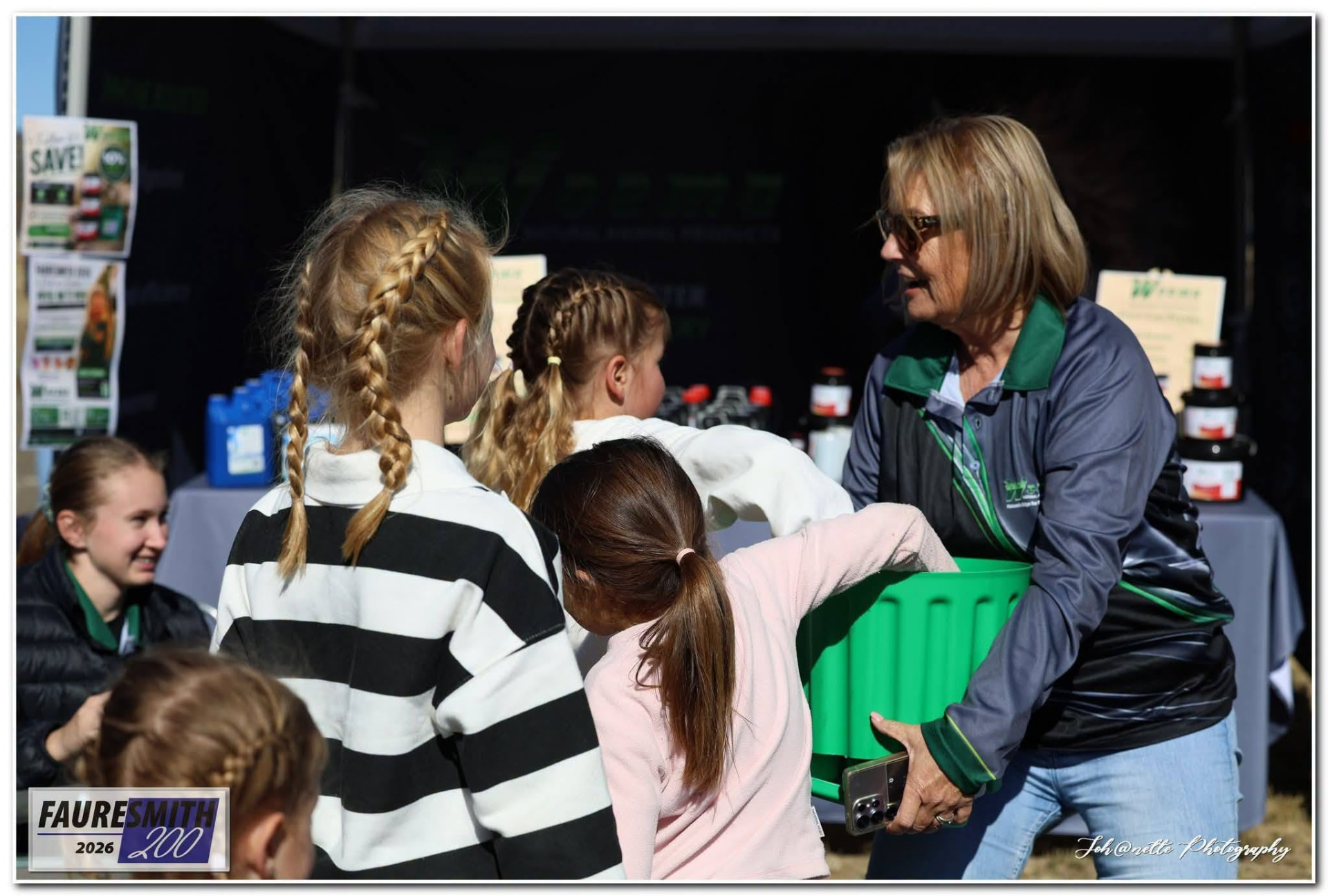 A WOEMA representative handing a tub to children at the Fauresmith 2026 stall